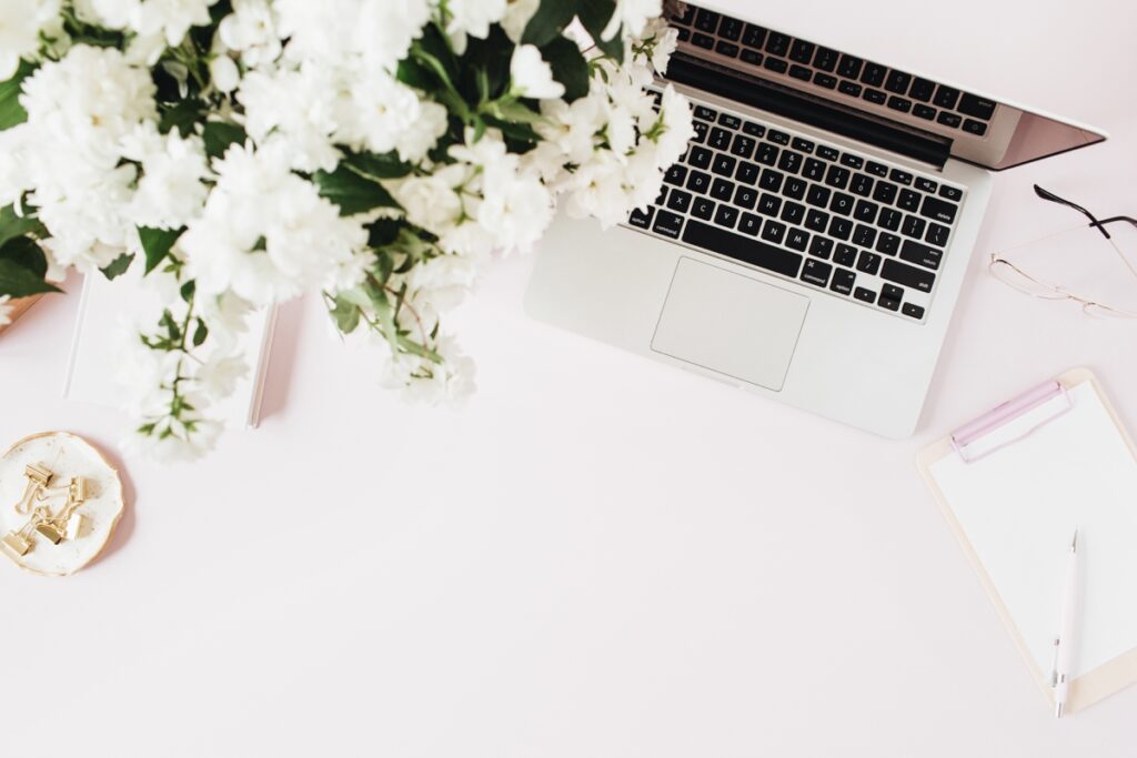 Rebecca Casey Photography blog post on Quitting Social media in 2025. A stock photo of a macbook on a desk with a clipboard and flowers. Wiltshire Photographer. Maternity Photographer in Wiltshire. Newborn Photographer in Wiltshire.