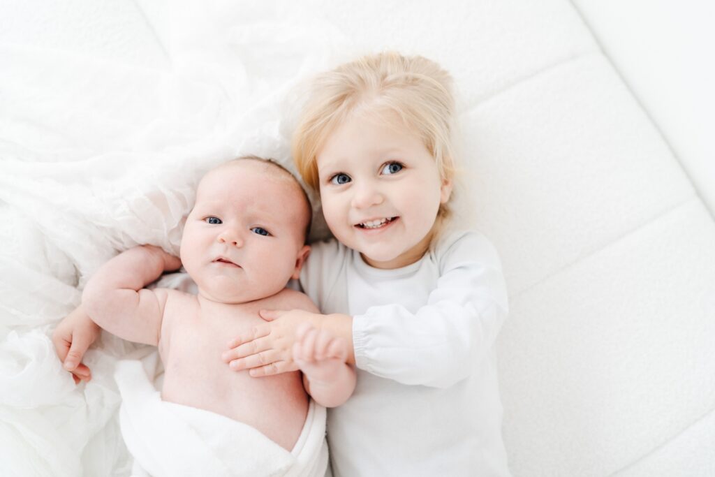 Big sister cuddling her baby brother during a baby photography session in Wiltshire