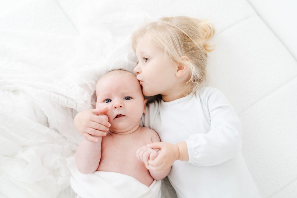 Big sister kissing her baby brother during a baby photography session in Wiltshire