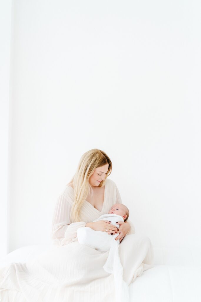 Mum cuddling her baby in a cream dress from the studio wardrobe during a light and airy baby photography session in Westbury.
